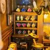 A miniature bookshelf filled with potion bottles, books, and other decorative items, suggesting a magical or alchemical theme. Voir les images du produit
