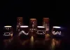 Several decorative candle holders with cut-out patterns are lit up in a dark room, casting a warm glow. Produktbild-Vorschau