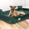 A dog is lying on a green dog bed on a wooden floor. Náhled obrázku produktu
