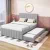 A grey upholstered bed with a pull-out trundle bed and storage drawers, set in a bedroom with pink and grey decor. Produktbild-Vorschau