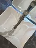 A close-up, high-angle shot of a white rectangular sink with a marble-like pattern and a dark gray faucet. Produktbild-Vorschau