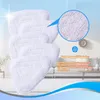 A stack of white microfiber mop pads with a close-up inset showing the texture of the material. The background is a bright, airy room with a sofa and coffee table, suggesting home use. Produktbild-Vorschau