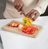 A person is chopping bell peppers on a wooden cutting board. Produktbild-Vorschau