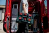 A person is carrying toolboxes out of a red van. Produktbild-Vorschau