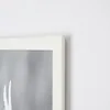 A close-up view of the corner of a white picture frame, showing a portion of the artwork inside. Náhľad obrázku produktu