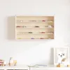 A wooden display cabinet filled with miniature cars, mounted on a white wall above a desk with children's toys and a framed picture. Voir les images du produit