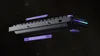A disassembled keyboard with purple accessories floating around it against a dark, starry background. Produktbild-Vorschau