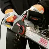 A person wearing gloves is using an electric chainsaw, creating sparks. Podgląd zdjęcia produktu