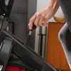 A close-up shot of a person's hand adjusting a knob on an indoor cycling bike. Voir les images du produit