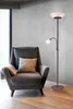 A floor lamp with a reading light next to an armchair in a room. Produktbild-Vorschau