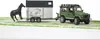 A toy Land Rover Defender towing a horse trailer with a toy horse. Produktbild-Vorschau