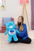 A young woman sits on the floor holding a blue plush bear. Produktbild-Vorschau