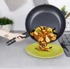 A hand is pouring paella from a frying pan onto a plate. The paella contains shrimp, mussels, peas, and lemon slices. Anteprima dell’immagine prodotto