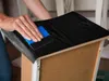 A person is applying a black wood-grain contact paper to the top of a drawer. Produktbild-Vorschau