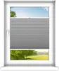 A window with a gray pleated blind partially covering the view of a green landscape with trees and a blue sky. Produktbild-Vorschau