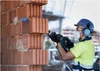A construction worker is using a reciprocating saw to cut into a brick wall. Voir les images du produit