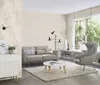 A living room with a sofa, armchair, coffee table, and a large window. Produktbild-Vorschau