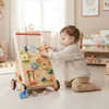 A baby playing with a wooden activity walker in a bright, airy room. Produktbild-Vorschau