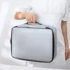 A person holding a gray document bag. Voir les images du produit