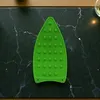 A green silicone iron rest pad is placed on a dark marble surface. Náhled obrázku produktu