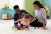 A family playing with baby toys on the floor. Produktbild-Vorschau