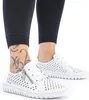 A close-up shot of a person's feet wearing white perforated sneakers and black leggings. Voir les images du produit
