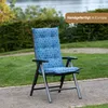 A blue and white patterned chair cushion is placed on a folding chair in an outdoor garden setting. Produktbild-Vorschau