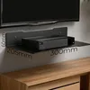 A black wall-mounted shelf holding a black electronic device, with dimensions indicated by text. Podgląd zdjęcia produktu