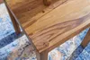 A close-up view of a wooden table surface with a patterned rug underneath. Náhled obrázku produktu