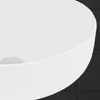 A close-up view of a white ceramic sink against a dark tiled background. Náhled obrázku produktu