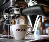 A close-up of a Costa branded coffee cup being filled with espresso from a coffee machine. Náhled obrázku produktu