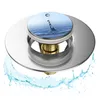 A pop-up drain stopper with a water droplet motif, shown with water splashing around it. Produktbild-Vorschau