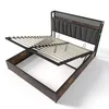 A bed frame with its mattress support system lifted to reveal storage space underneath. Voir les images du produit