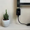 A small cactus in a white pot sits on a shelf next to a black heating element with a dial. Náhľad obrázku produktu