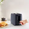 A hand is shown adjusting the dial on a dark gray Tefal toaster, with a cup of coffee and toast in the foreground. Produktbild-Vorschau