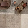 A cozy living room scene with a rug, ottoman, candle, and decorative tray. Produktbild-Vorschau