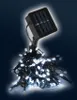 A string of white LED lights with a solar panel attached. Produktbild-Vorschau