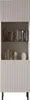 A tall, narrow display cabinet with fluted detailing on the doors and sides, standing on black metal legs. The shelves inside hold books and decorative items. Náhled obrázku produktu