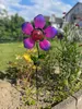 A solar garden stake shaped like a flower with glass petals is planted in a garden bed. Produktbild-Vorschau