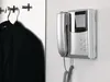 An intercom system is mounted on a wall next to a coat rack with a black jacket hanging on it. Podgląd zdjęcia produktu