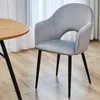A gray upholstered dining chair with black legs is shown next to a round wooden table. Produktbild-Vorschau