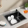 A kitchen sink with dishes drying in a rack, and some fruit on the counter. Produktbild-Vorschau