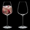 Two wine glasses on a black background. One glass is filled with a pink drink, ice, and berries. The other glass is empty. Produktbild-Vorschau