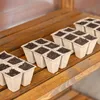 Seedling trays filled with soil sit on a wooden shelf. Voir les images du produit