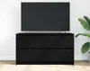 A black TV stand with a television on top, placed against a white wall with a plant to the right. Podgląd zdjęcia produktu