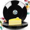 A stack of black dessert plates with a slice of lemon cake on top, surrounded by macarons. Podgląd zdjęcia produktu