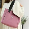 Rosa Stofftasche mit schwarzem Riemen, über der Schulter einer Person in weißer Jacke getragen Náhľad obrázku produktu
