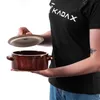 A person is holding a brown ceramic pot with a lid. Produktbild-Vorschau