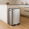 A stainless steel dual-compartment kitchen trash can with foot pedals is shown in a modern kitchen setting. Náhled obrázku produktu