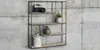 A modern wall shelf with a black metal frame and wooden shelves, decorated with a camera, plants, and a vase. Produktbild-Vorschau
